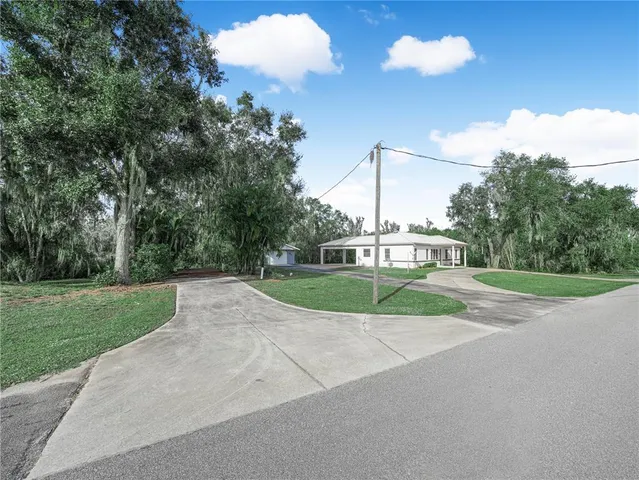 a view of a house with a big yard and a large trees