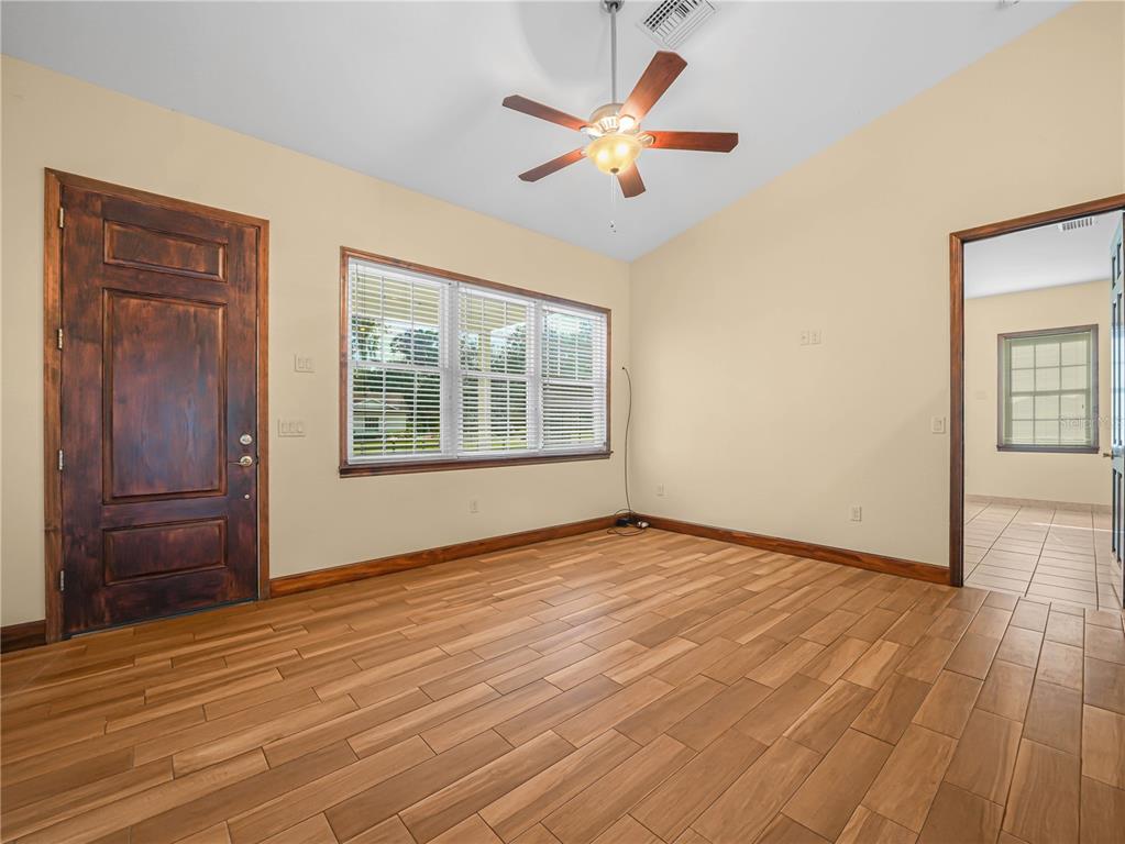 100 Reedy Creek Drive Frostproof, FL 33843 - Photo 3 of 36 an empty room with wooden floor chandelier fan and windows