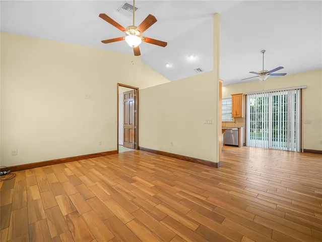 a view of an empty room with glass door and a chandelier fan