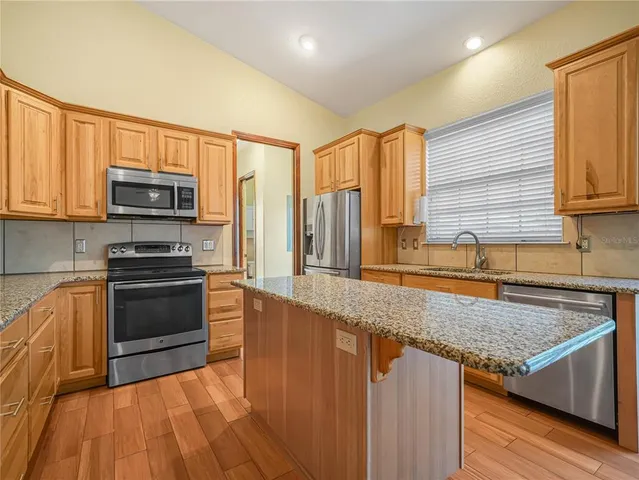 a kitchen with stainless steel appliances granite countertop a stove a sink and a microwave