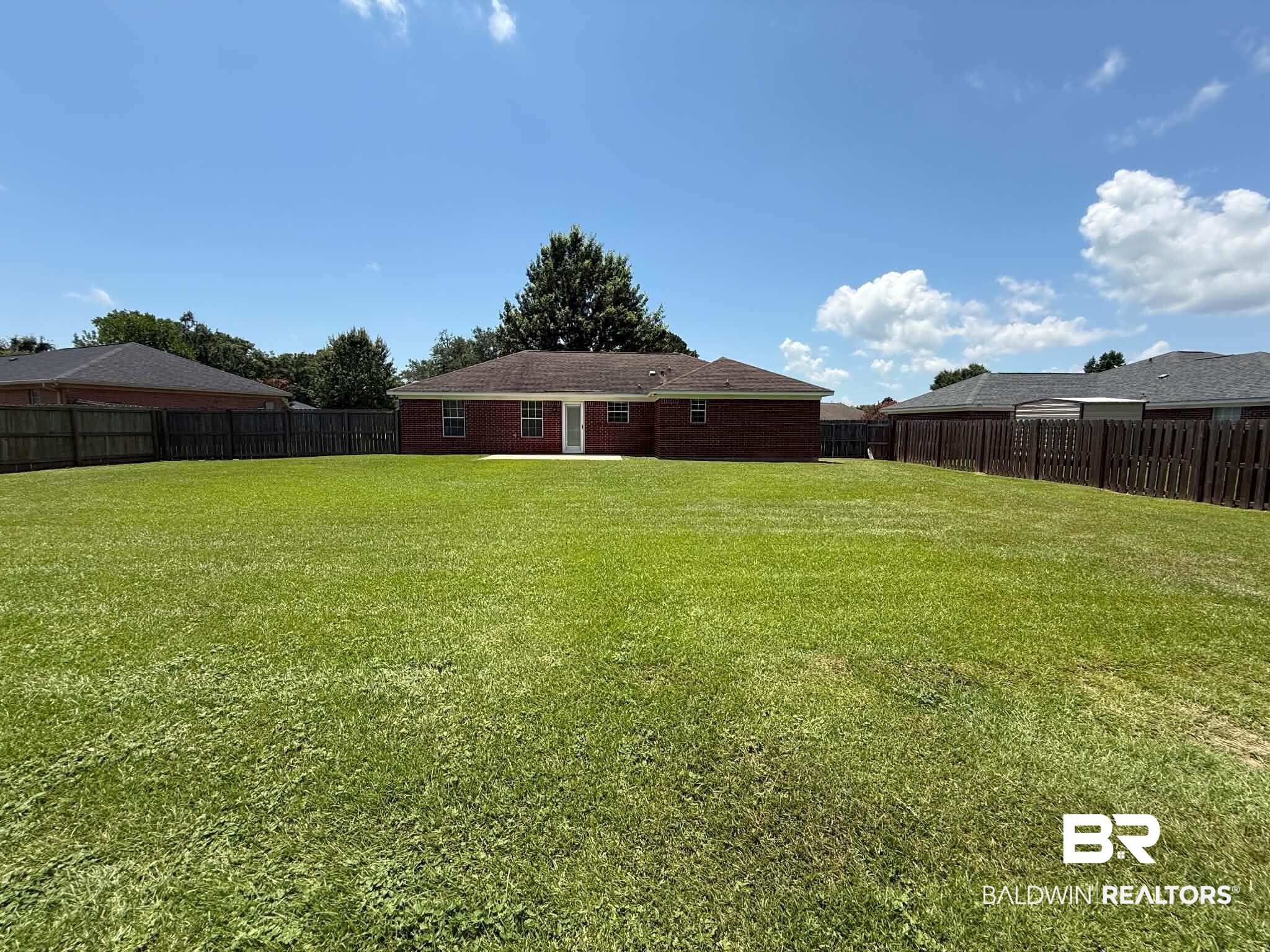123 Pennbrooke Loop Foley, AL 36535 - Photo 9 of 49 Expansive rear yard featuring a brick exterior home, large green lawn, full perimeter wood fencing, and an exterior patio