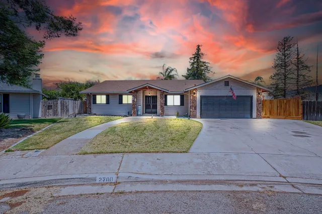 a view of a white house with a yard and large tree