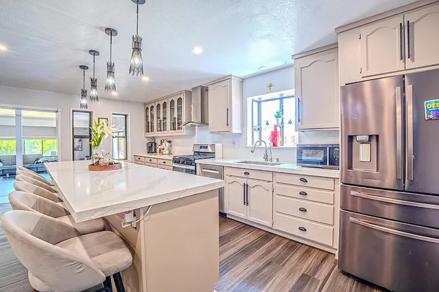 a large kitchen with kitchen island granite countertop a large counter top a sink a window and stainless steel appliances