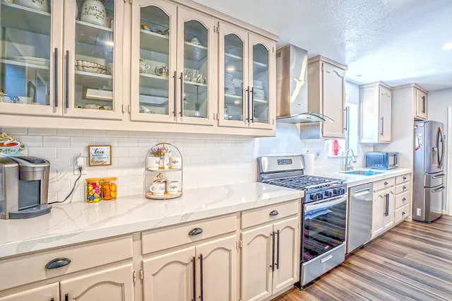 a kitchen with stainless steel appliances granite countertop a dining table chairs stove refrigerator and cabinets