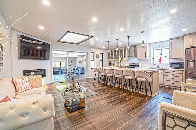 a kitchen with stainless steel appliances granite countertop a dining table chairs refrigerator and microwave