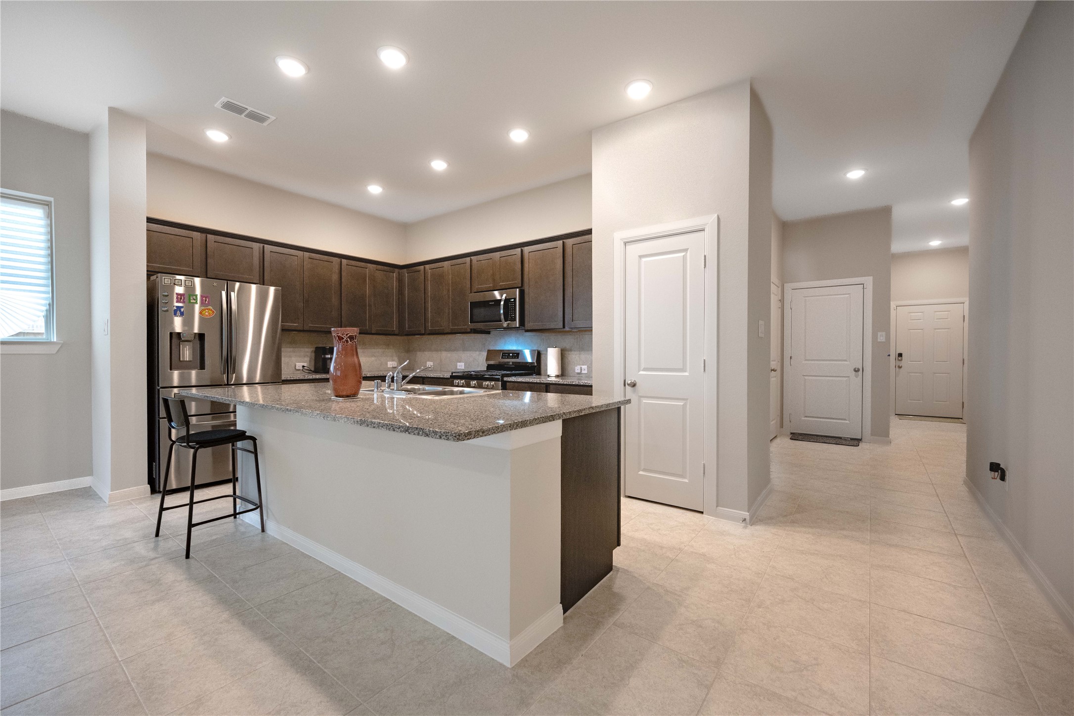 9026 Red Wolf Place Manvel, TX 77578 - Photo 3 of 17 a kitchen with stainless steel appliances kitchen island granite countertop a refrigerator and a sink