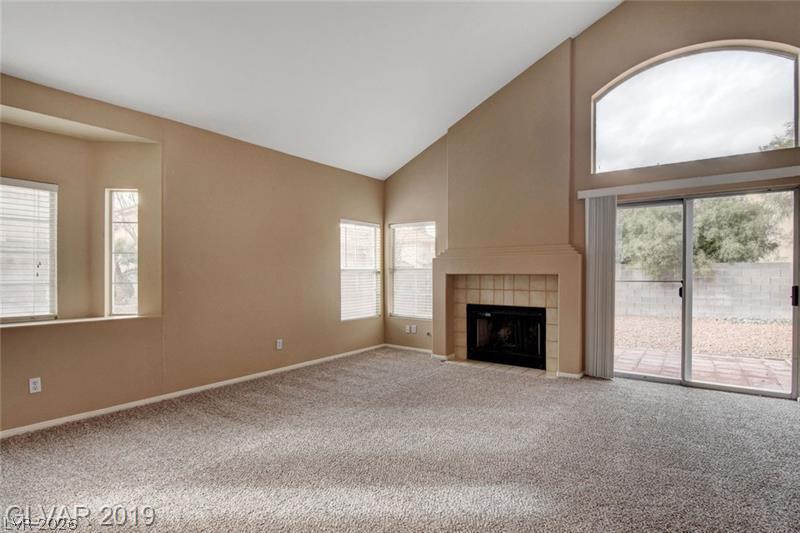 2647 Ridgewater Circle Henderson, NV 89074 - Photo 10 of 26 Vaulted ceilings and a tile-accented fireplace define this welcoming living space with backyard access.