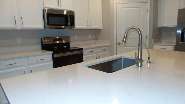 a kitchen with stainless steel appliances a stove a sink a microwave and cabinets