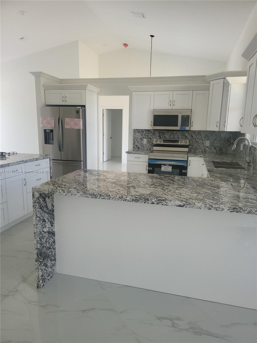 Goulds Miami, FL 33170 - Photo 3 of 5 a kitchen with kitchen island granite countertop a stove and a sink with cabinets