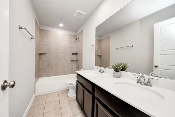 a bathroom with a double vanity sink toilet mirror and bathtub