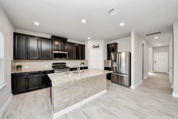 a large kitchen with stainless steel appliances cabinets a sink and a stove