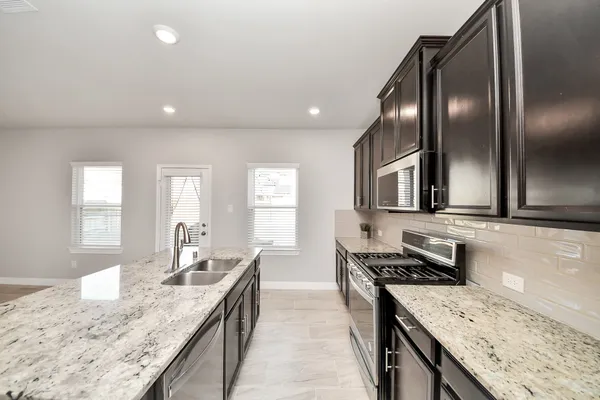 a kitchen with stainless steel appliances granite countertop a sink stove and refrigerator