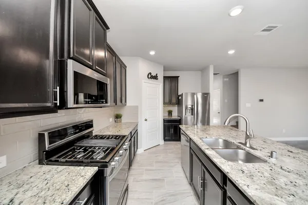 a kitchen with stainless steel appliances granite countertop a sink stove and refrigerator