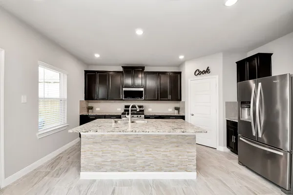 a large kitchen with kitchen island granite countertop a sink a counter top space stainless steel appliances and cabinets