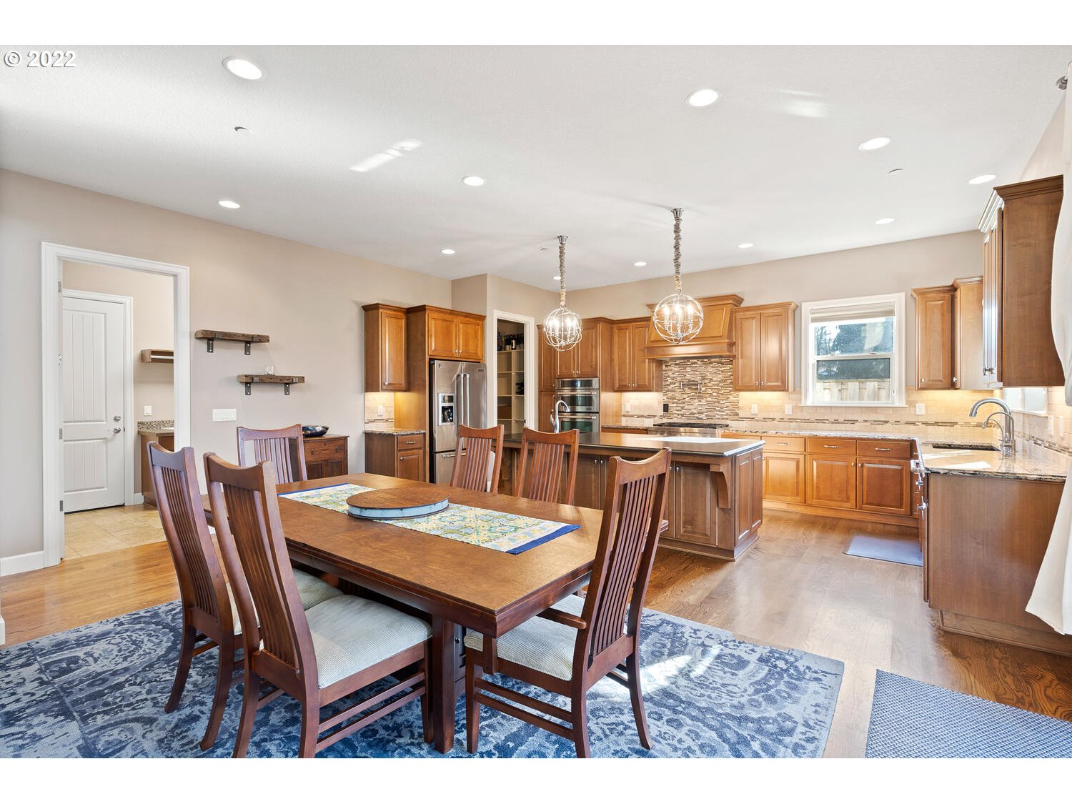 6117 Southwest 67th Place Portland, OR 97223 - Photo 8 of 32 a dining room with stainless steel appliances kitchen island granite countertop a dining table chairs and a refrigerator