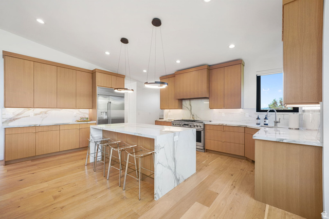 3667 Little Cottonwood Road, Unit 1 Sandy, UT 84092 - Photo 11 of 49 Spacious kitchen featuring an oversized island with waterfall countertop, stainless steel appliances, light wood-finish cabinetry, and recessed lighting