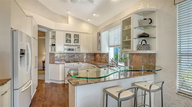 a kitchen with stainless steel appliances granite countertop white cabinets and a window