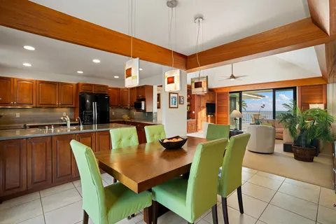 a dining room with stainless steel appliances granite countertop a dining table chairs and a living room view