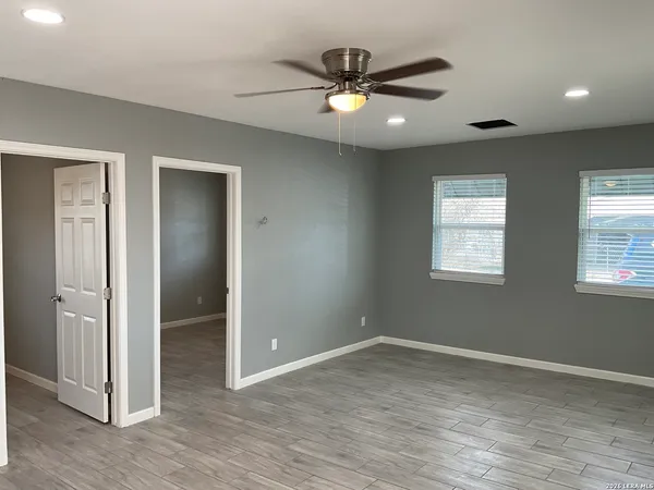 a view of an empty room with wooden floor and a window