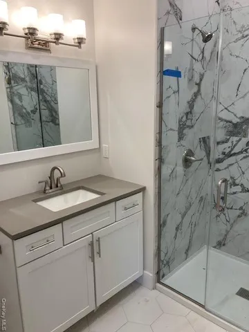 a bathroom with a granite countertop sink a mirror and shower