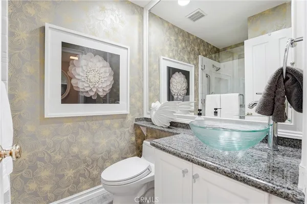 a bathroom with a granite countertop sink mirror vanity and toilet