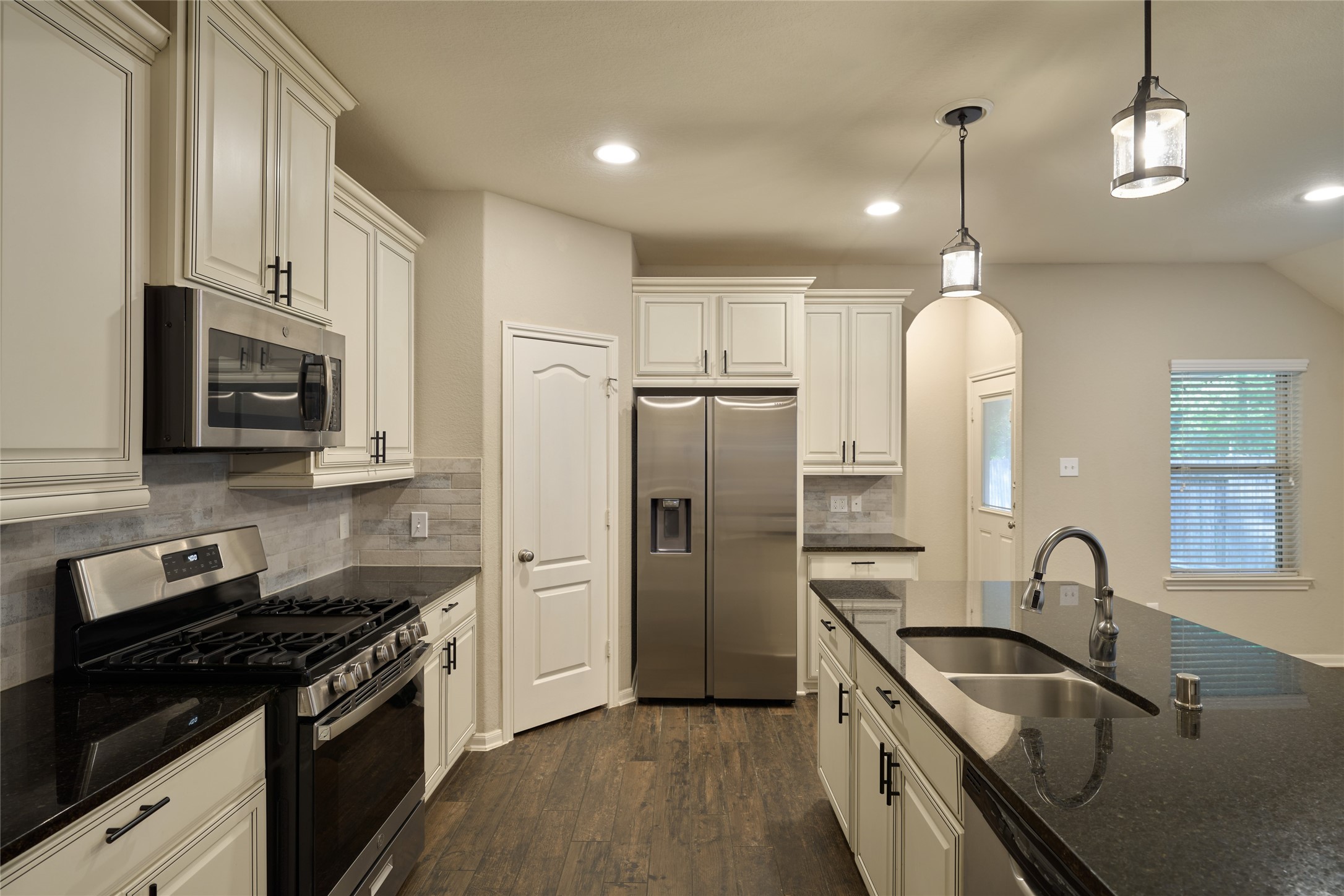 116 Fox Trail Road Montgomery, TX 77316 - Photo 19 of 50 The kitchen features modern stainless steel appliances- refrigerator included, granite countertops, and elegant cabinetry. It includes a central island with a sink, pendant lighting, and ample natural light through a nearby window.
