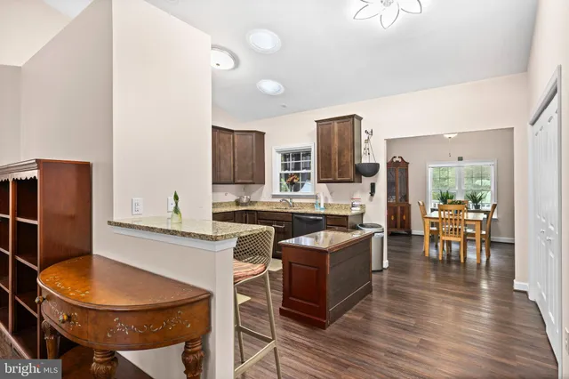 a kitchen with stainless steel appliances granite countertop a sink a stove a dining table and chairs