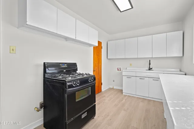 a kitchen with stainless steel appliances a stove and white cabinets