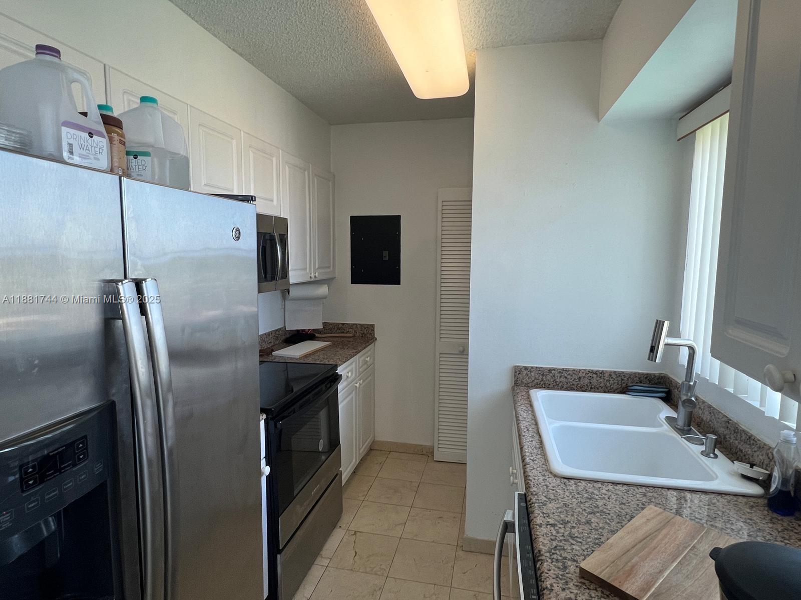 5900 Collins Avenue, Unit 1505 Miami Beach, FL 33140 - Photo 10 of 18 a kitchen with a refrigerator sink and stove