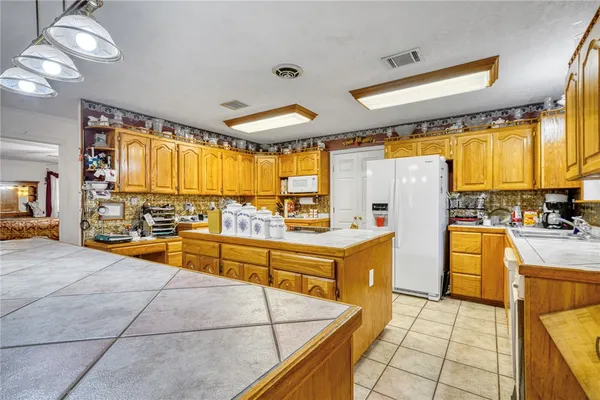 a kitchen with stainless steel appliances kitchen island granite countertop a refrigerator and a stove top oven