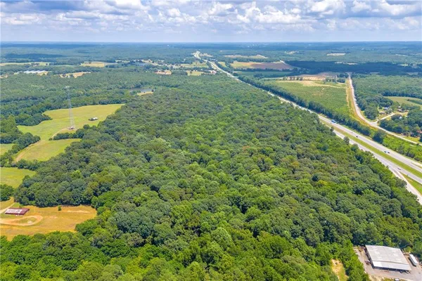 an aerial view of a houses with outdoor space and trees all around