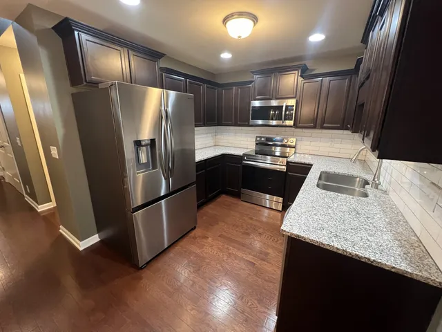 a kitchen with granite countertop stainless steel appliances a refrigerator a stove a sink and a oven