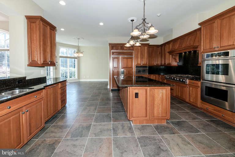 903 Georgetown Ridge Court McLean, VA 22102 - Photo 12 of 29 a large kitchen with stainless steel appliances granite countertop a stove top oven a large island a dining table and chairs