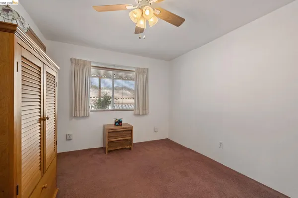 an empty room with windows and ceiling fan