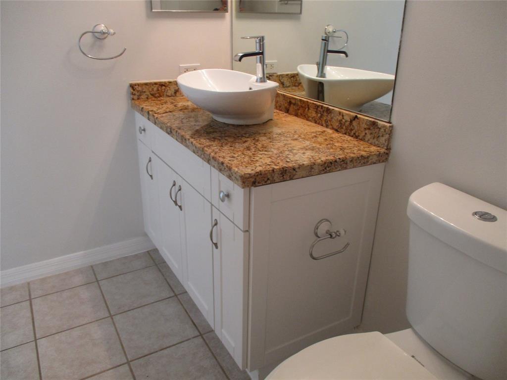5045 Wiles Road, Unit 206 Coconut Creek, FL 33073 - Photo 12 of 24 a bathroom with a granite countertop sink a toilet and a mirror