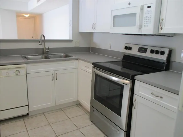a kitchen with granite countertop white cabinets stainless steel appliances and sink