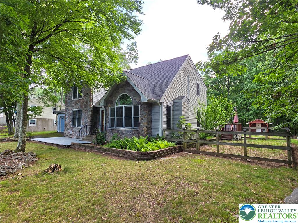211 Murphy Circle Bushkill, PA 18324 - Photo 2 of 28 Stone and siding exterior offers curb appeal with a landscaped garden bed and a fenced yard.