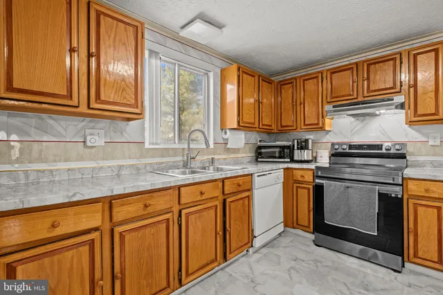 a kitchen with granite countertop cabinets stainless steel appliances a sink and window