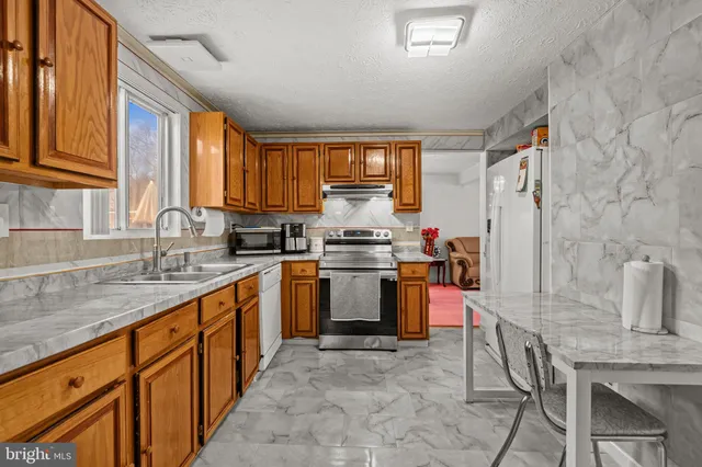a kitchen with granite countertop a sink stove and cabinets