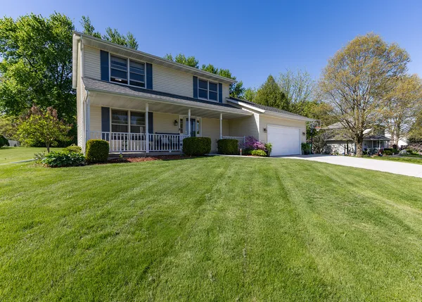 a view of a yard in front of a brick house with plants and large trees