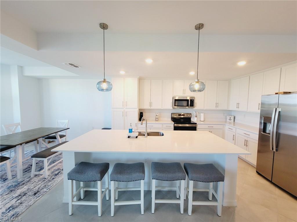 43997 Boardwalk Loop, Unit 1832 Babcock Ranch, FL 33982 - Photo 6 of 22 a kitchen with stainless steel appliances a stove a refrigerator a kitchen island a table and chairs
