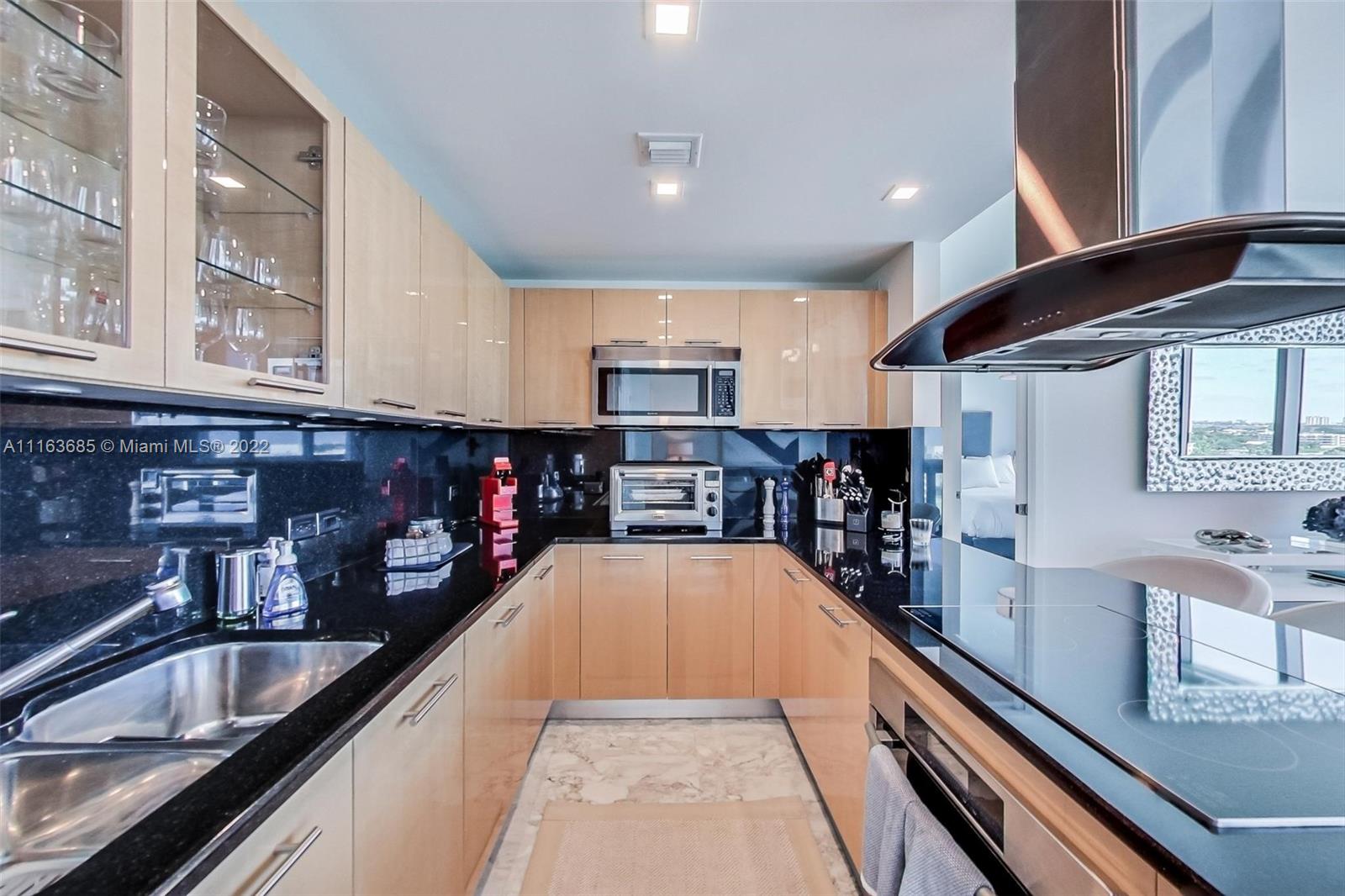 6899 Collins Avenue, Unit 910 Miami Beach, FL 33141 - Photo 13 of 46 a large kitchen with stainless steel appliances granite countertop a large counter top and a stove