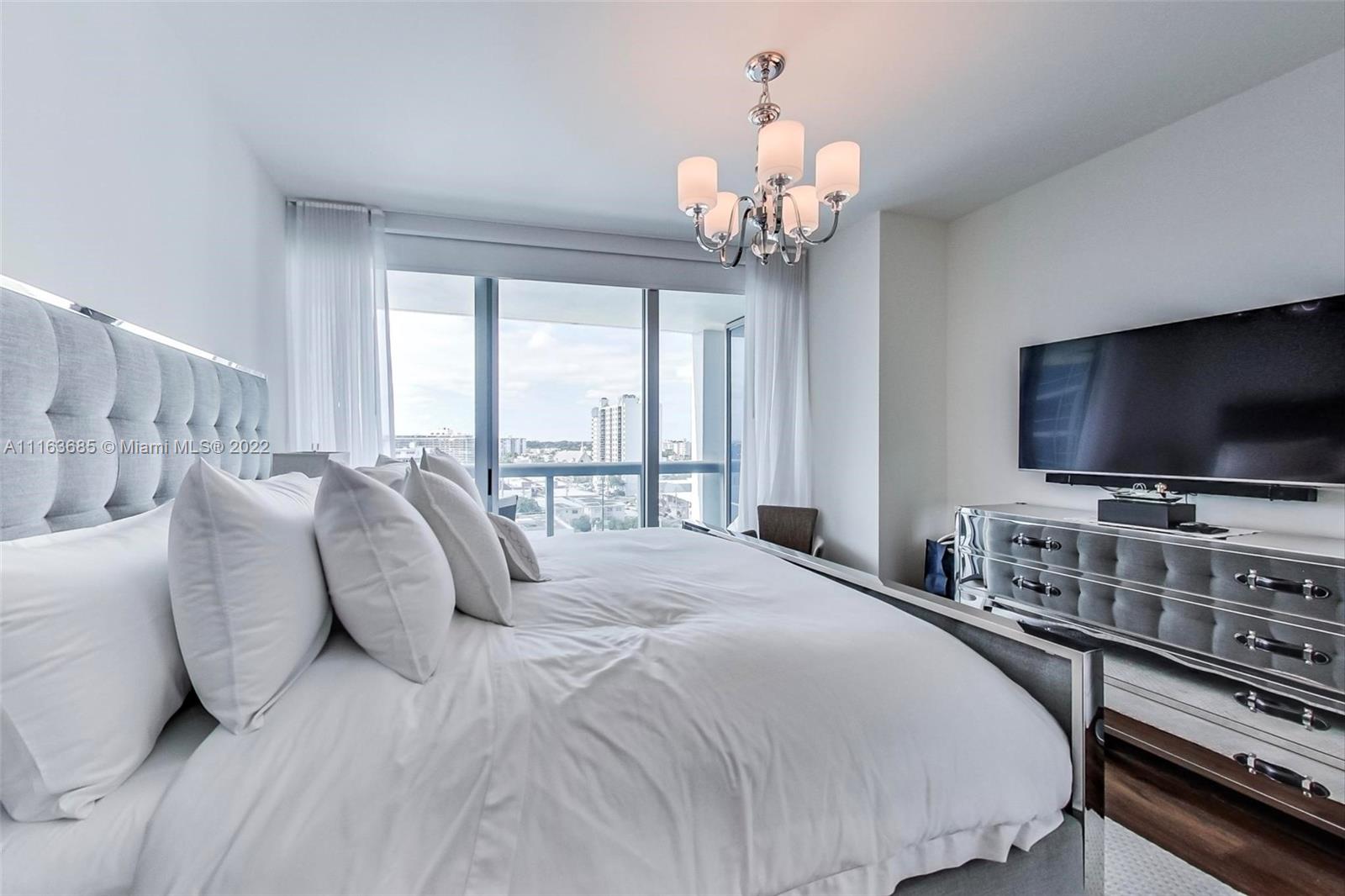 6899 Collins Avenue, Unit 910 Miami Beach, FL 33141 - Photo 16 of 46 a spacious bedroom with a bed and a flat screen tv