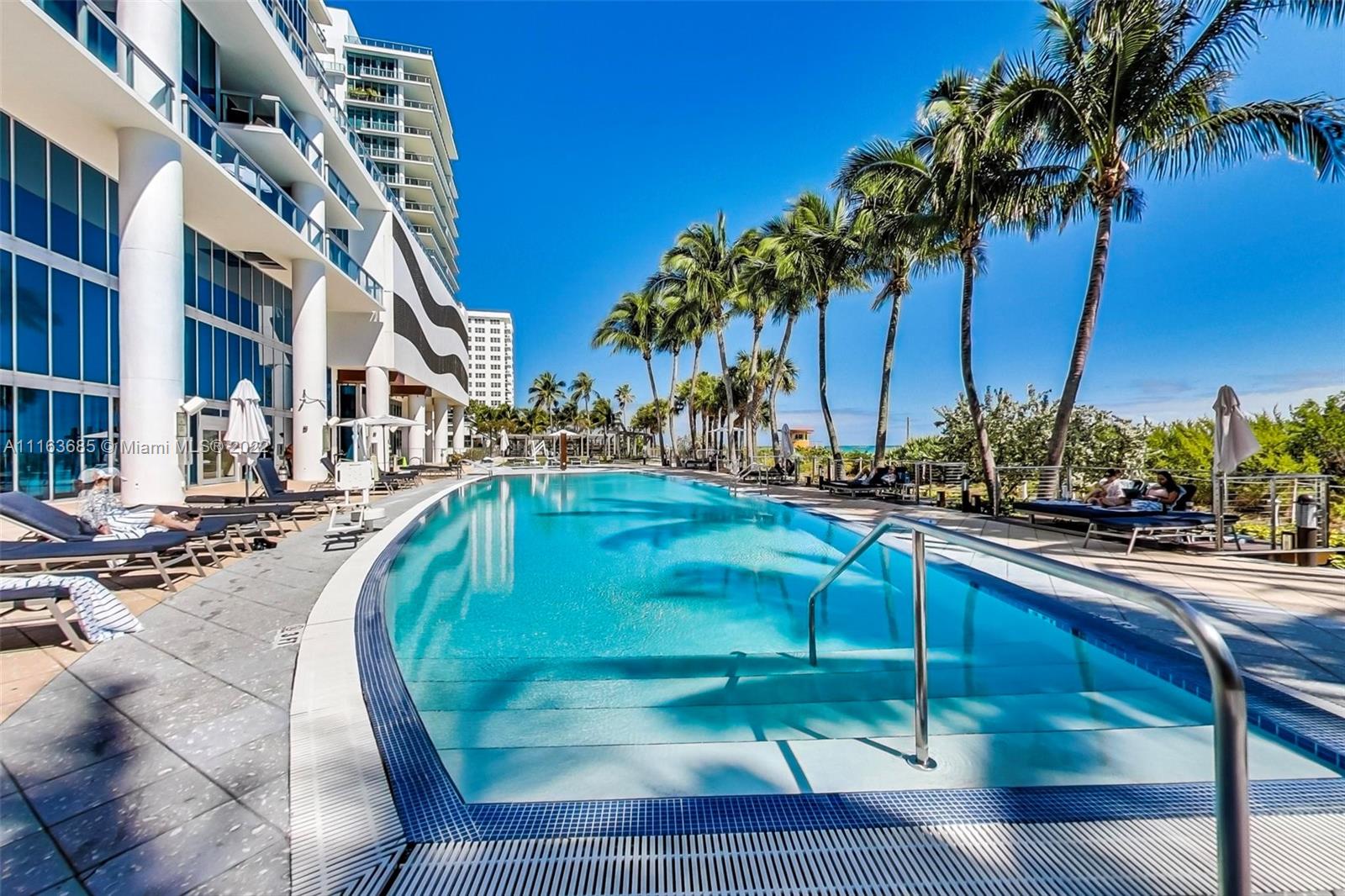 6899 Collins Avenue, Unit 910 Miami Beach, FL 33141 - Photo 38 of 46 a view of a swimming pool with a chair and palm trees