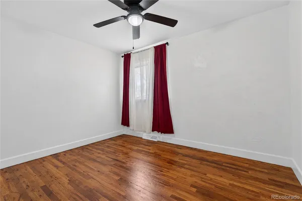 a view of a room with wooden floor and a ceiling fan