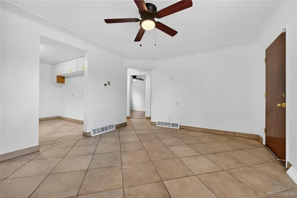a view of an empty room and chandelier fan