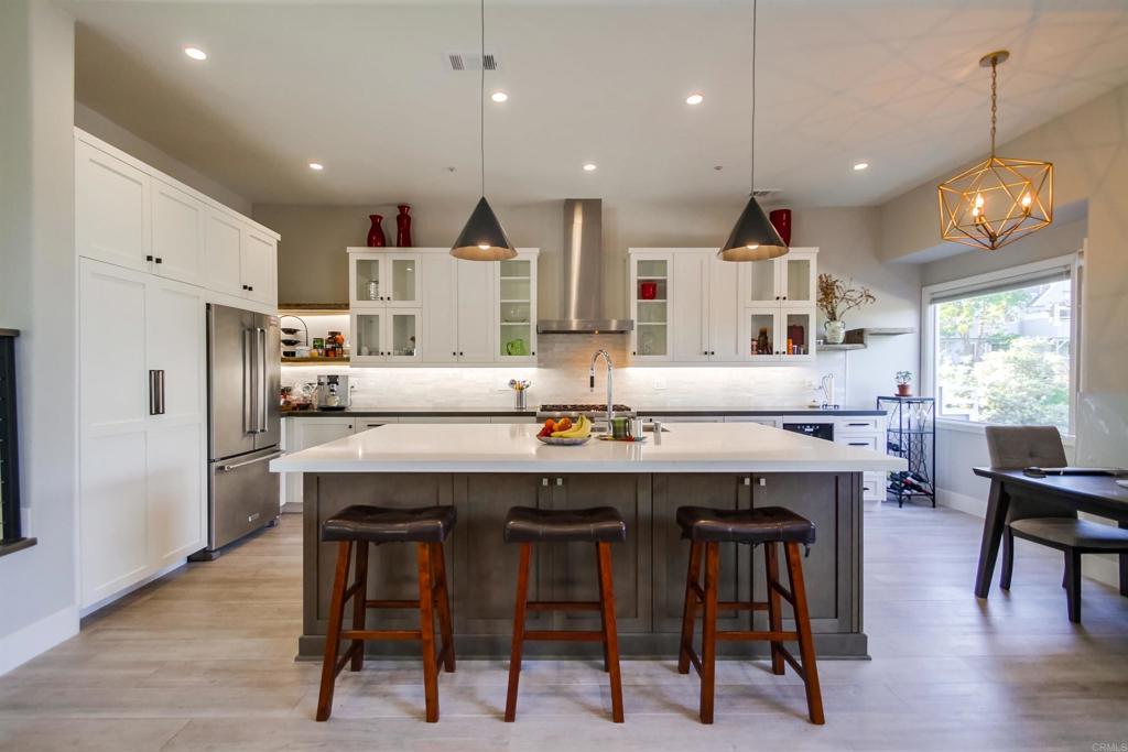 864 Del Mar Downs Road Solana Beach, CA 92075 - Photo 6 of 20 a kitchen with stainless steel appliances kitchen island granite countertop a dining table chairs and white cabinets