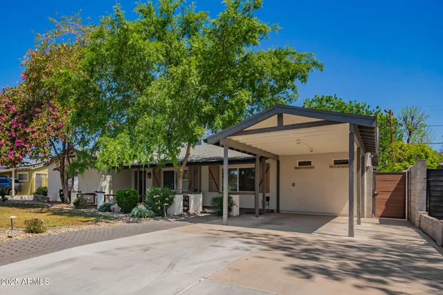 a front view of a house with a yard and potted plants