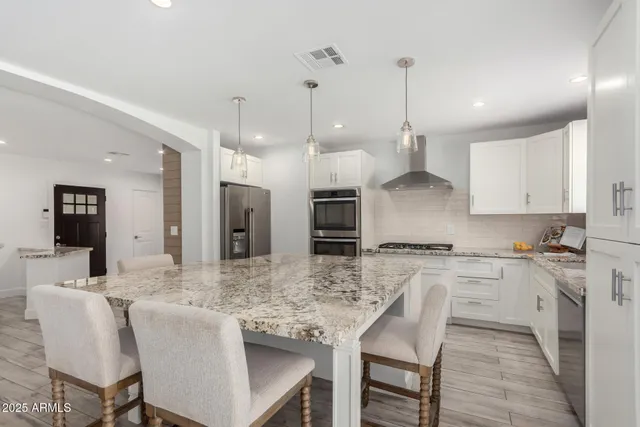 a kitchen with granite countertop a stove a sink a kitchen island with a dining table and chairs