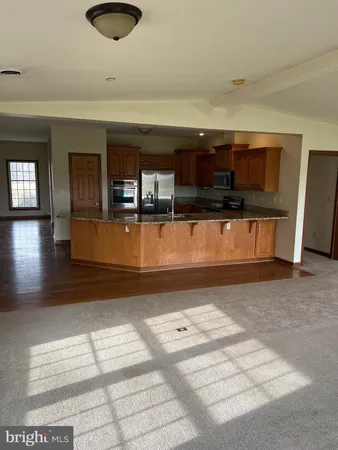a view of kitchen and empty room with wooden floor